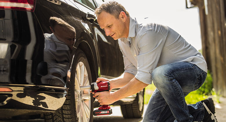 man working with an impact screwdriver on a car