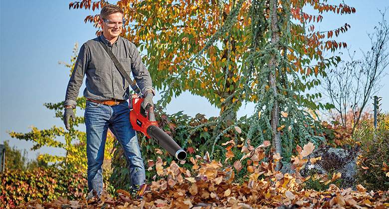 a man blows away the leaves with a leaf blower